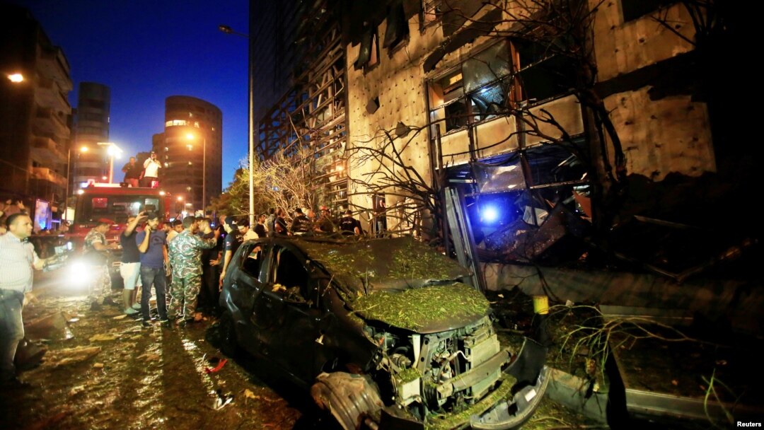 A wrecked vehicle is seen as policemen and civilians inspect the site of an explosion at Blom Bank in Beirut, Lebanon, June 12, 2016.