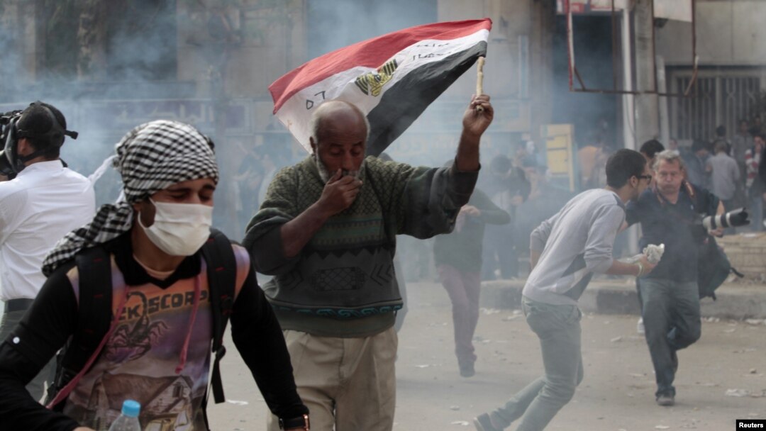 Anti-Morsi protesters run for cover during clashes with riot police at Tahrir Square in Cairo, November 27, 2012. 