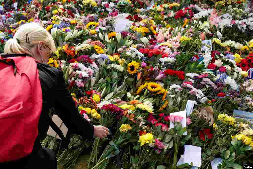 A woman leaves flowers at Hillsborough Castle, following the death of Britain's Queen Elizabeth, at Royal Hillsborough, Northern Ireland.
