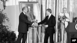 FILE - President Jimmy Carter shakes hands with former President Gerald R. Ford in the White House in Washington on May 24, 1978, during a ceremony at which a portrait of Ford was unveiled.