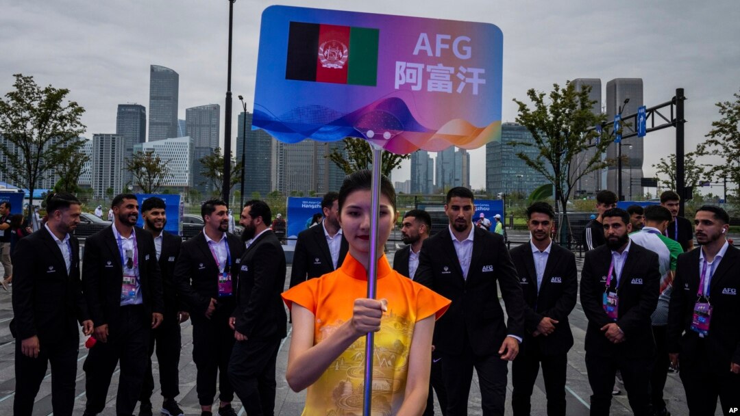 在中國杭州舉行的第19屆亞運會歡迎儀式上，一名志願者舉牌站在阿富汗塔利班政權派出的全部為男性運動員的隊伍前。（2023年9月20日）