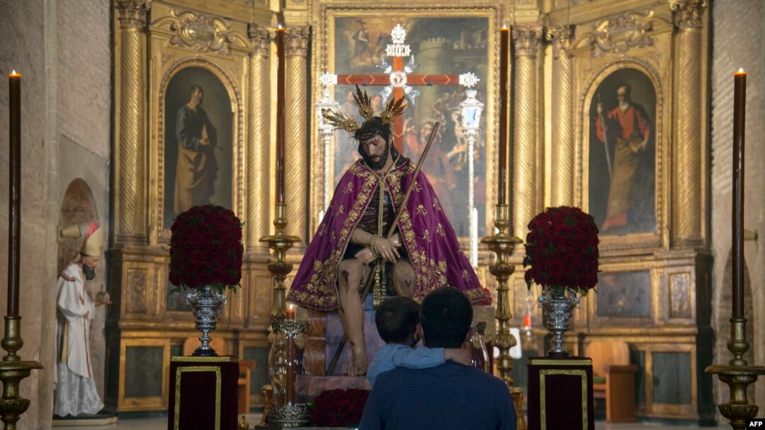 FILE - A father and his son look at a figure of Jesus Christ at San Esteban church, in Seville, Spain, on March 30, 2021. 