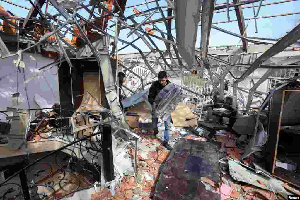 A man salvages items at a damaged site that was hit by an airstrike on Monday, after what Lebanon's state media said was a series of Israeli strikes around Ghaziyeh on Lebanon's coast 60 km north of the border with Israel.