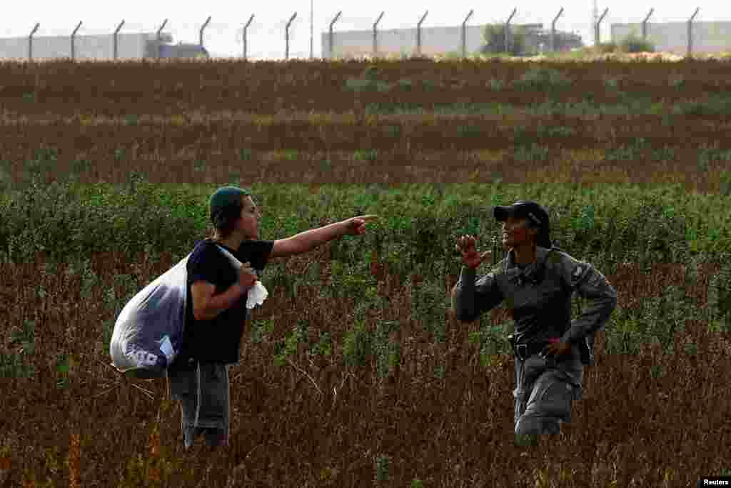 Israeli border police stop a man from heading to a protest against the delivery of humanitarian aid to Gaza and demand the immediate release of Israeli hostages kidnapped in the deadly October 7 attack, at the Kerem Shalom Crossing, as trucks waiting to enter Gaza from Egypt are seen in the background.