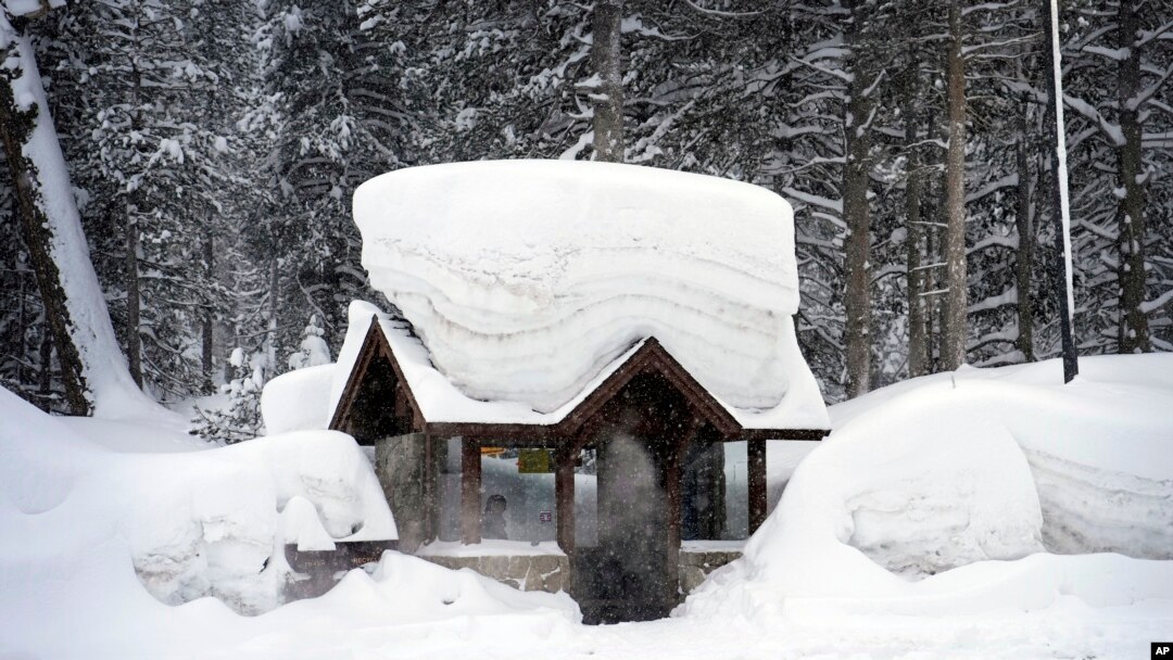 A person sits in a snow-covered bus stop Feb. 24, 2023, in Olympic Valley, California.