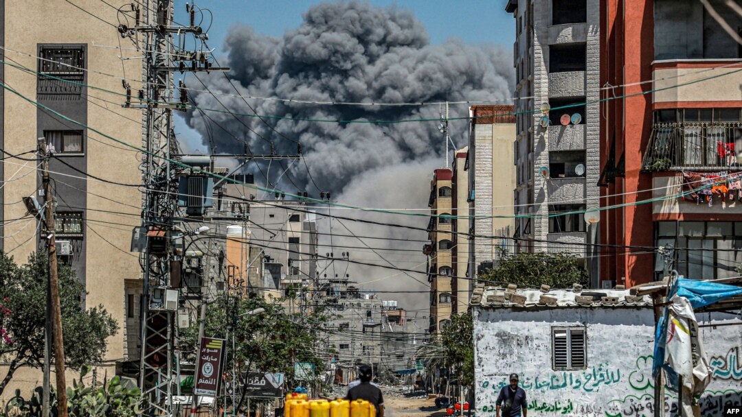 A cloud of smoke erupts down the road from an explosion in Nuseirat in the central Gaza Strip on April 17, 2024.