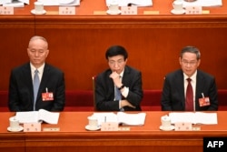资料照：左起：中共中央政治局常委蔡奇、王沪宁（左）与李强在人大会堂出席全国人大会议。（2023年3月7日）