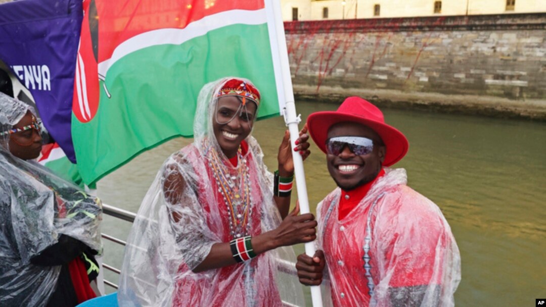 Trizah Atuka and Ferdinand Omanyala, flag bearers for Kenya, are seen on the team's boat as it makes its way along the Seine in Paris, France, during the opening ceremony for the 2024 Summer Olympics, July 26, 2024.