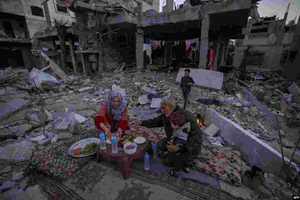 The Palestinian Al-Naji family prepares to break their fast during the first day of the Muslim holy fasting month of Ramadan sitting amidst the ruins of their family house in Deir el-Balah, central Gaza Strip, March 11, 2024.