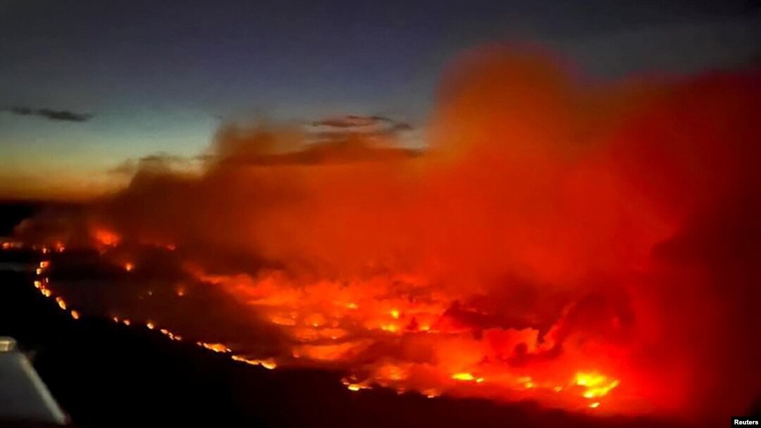 FILE - The Parker Lake wildfire glows in a photograph taken by a B.C. Emergency Health Services crew member through the window of an airplane evacuating patients from nearby Fort Nelson, British Columbia, Canada, May 10, 2024. 