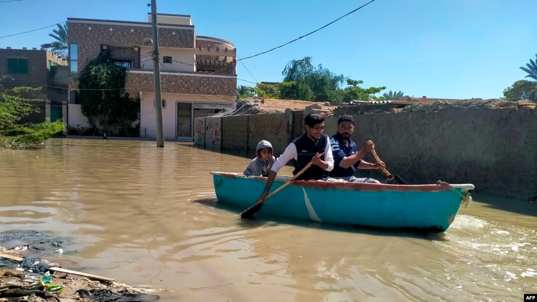 Residents row a boat to cross a flooded street after heavy rains in Gwadar in Balochistan province on March 2, 2024.