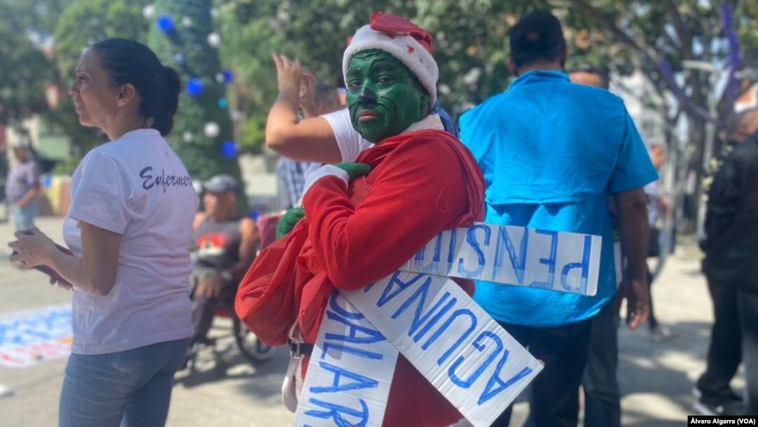 Trabajadores activos y jubilados de Venezuela, uno de ellos disfrazado del personaje el Grinch, se manifiestan por mejores salarios, el pago completo de aguinaldos y pensiones más "dignas" en Caracas, el 9 de noviembre de 2023.