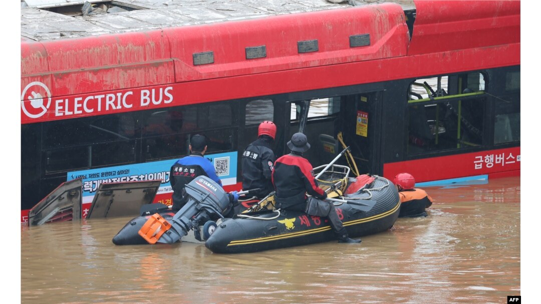 South Korean rescue workers search for missing persons near a bus along a deluged road leading to an underground tunnel where some 15 cars were trapped in flood waters after heavy rains in Cheongju, July 16, 2023. (Photo by YONHAP/AFP)