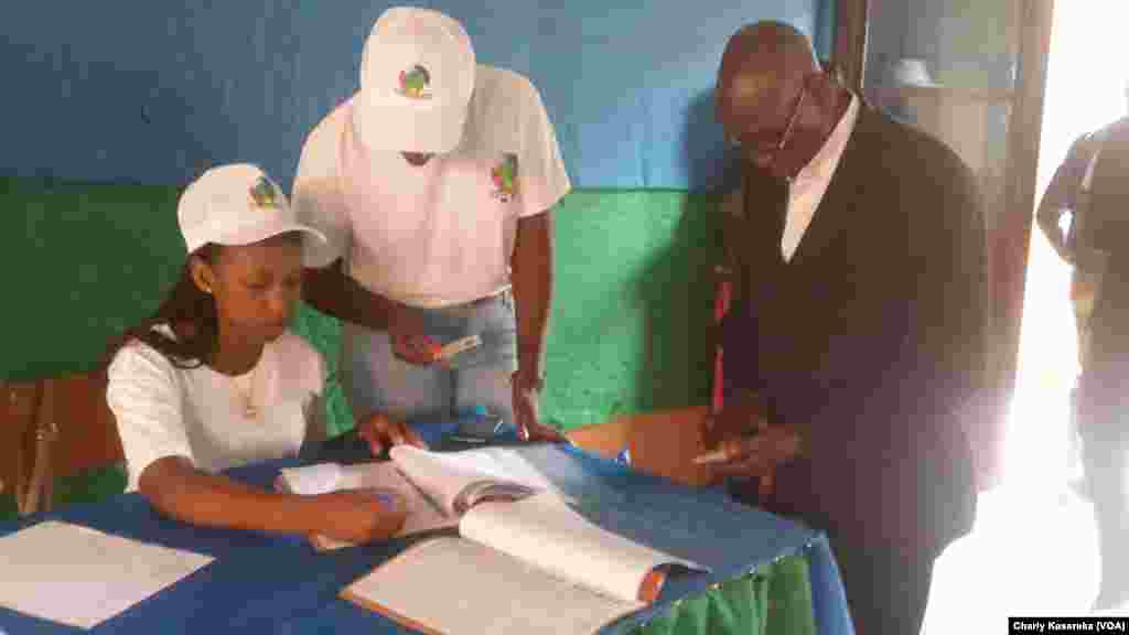 Officials check a voter's ID at a polling station in Kigali, Aug. 4, 2017. (Photo: Charly Kasereka/ VOA)