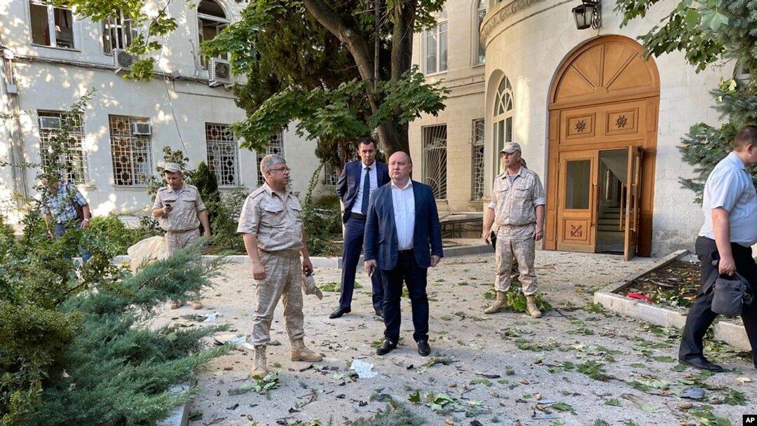 In this handout photo released by Sevastopol governor Mikhail Razvozhaev's Telegram channel July 31, 2022, Razvozhayev, center, stands at the scene of explosion at the headquarters of Russia's Black Sea Fleet in Sevastopol, in Russia-annexed Crimea. 