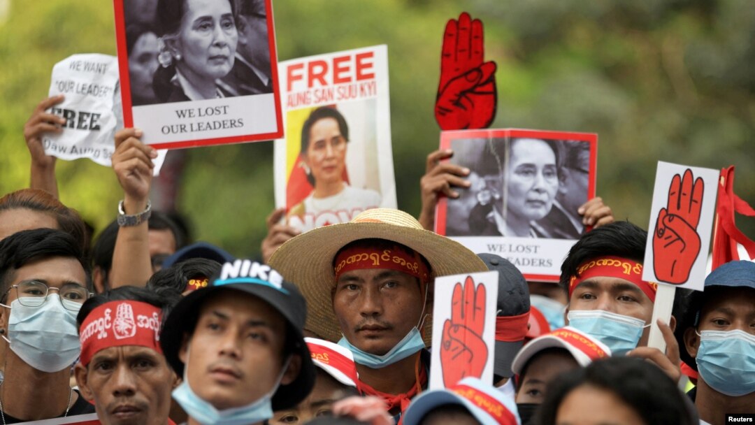 FILE - Demonstrators hold placards with pictures of Aung San Suu Kyi as they protest against the military coup in Yangon, Myanmar, Feb. 22, 2021. 
