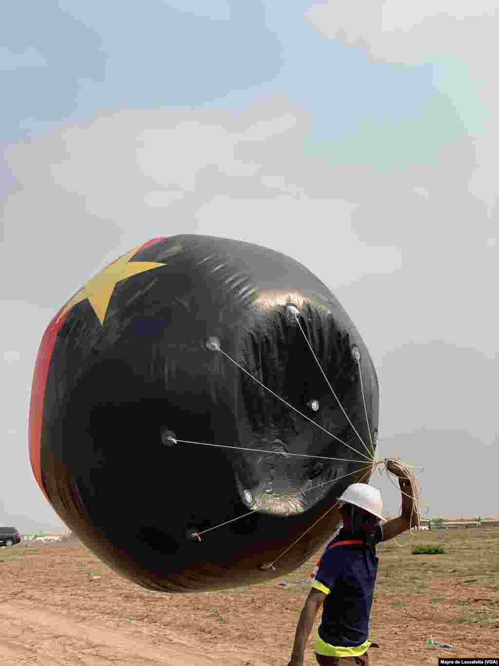 Um jovem carrega um balão com o símbolo e cores do partido MPLA. Camama, Luanda.
