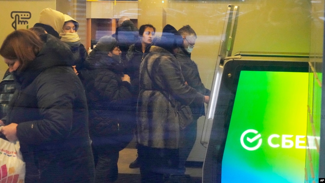 FILE - People stand in line to withdraw money from an ATM in Sberbank in St. Petersburg, Russia, Feb. 25, 2022.