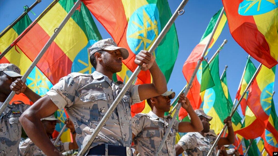 Members of the Ethiopian National Defense Force hold national flags as they parade during a ceremony to remember soldiers who died on the first day of the Tigray conflict, outside the city administration office in Addis Ababa, Ethiopia, Nov. 3, 2022. 