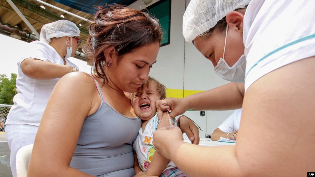 FILE - A Venezuelan woman and her baby are vaccinated against measles in Cucuta, Colombia, at the international brigde Simon Bolivar on the border with Venezuela, on March 21, 2018. 