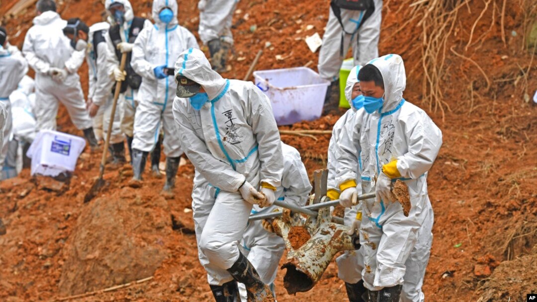 FILE - In this photo released by Xinhua News Agency, rescuers carry a piece of plane wreckage at the site of Monday's plane crash in Tengxian County, southern China's Guangxi Zhuang Autonomous Region, on March 25, 2022.