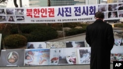 FILE - A man watches photos showing North Korean children suffering from famine at a photo exhibition in Seoul, South Korea, Feb. 27, 2014.