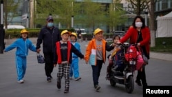 北京一所小学校的家长在接放学的孩子回家。（2021年4月6日）