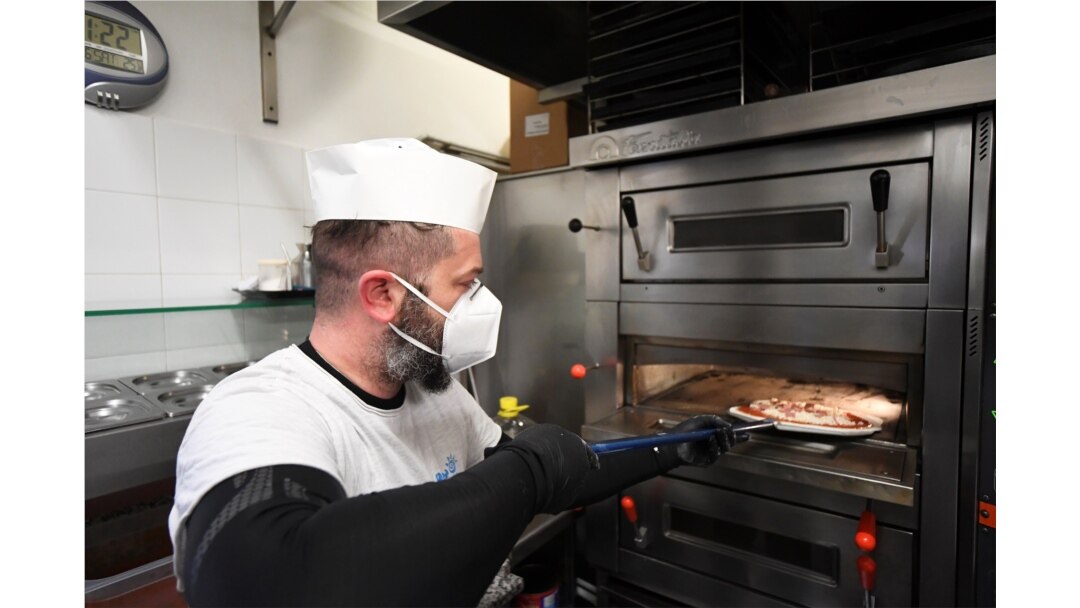 A man bakes a pizza at a restaurant, as Tuscany is the first Italian region to allow restaurants to open only for takeout in Castiglione della Pescaia, April 27, 2020.