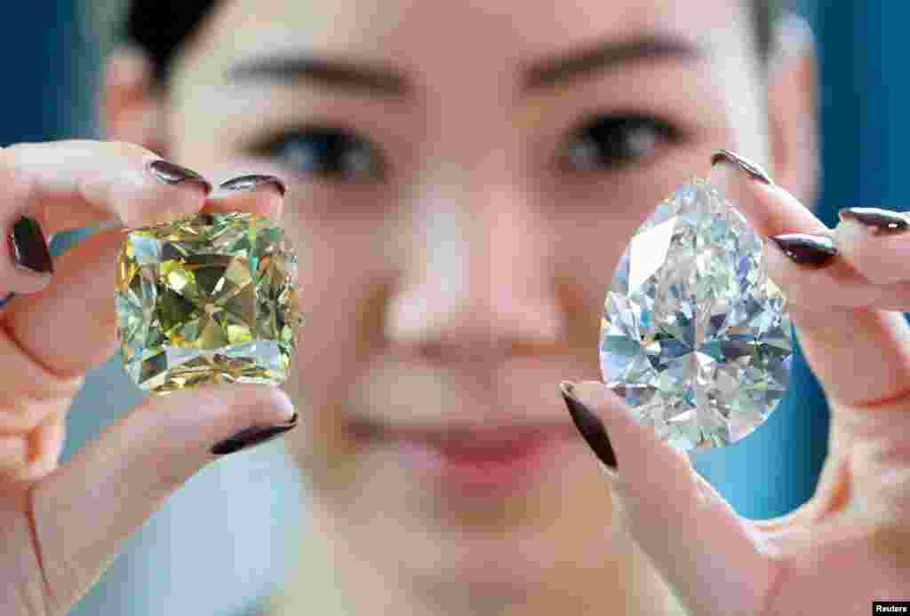 Returning for the third time since its mining in 1901, the "Red Cross" — a fancy intense yellow, cushion-shaped 205.07 carat diamond — and a 228.31 carat white diamond called "The Rock" that could fetch $30 million and is the largest ever seen throughout auction market history are pictured during a preview at Christie's before their auction sale in Geneva, Switzerland.
