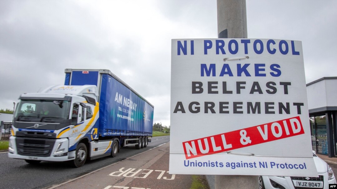 A truck passes an anti 'Northern Ireland Protocol' sign as it is driven away from Larne port, north of Belfast in Northern Ireland, after arriving on a ferry, May 17, 2022. 