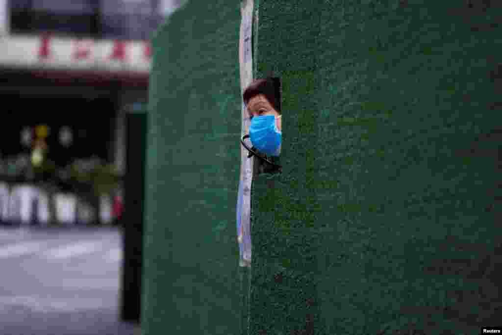 A resident looks out through a gap in the barrier at a residential area during lockdown, amid the COVID-19 pandemic, in Shanghai, China.