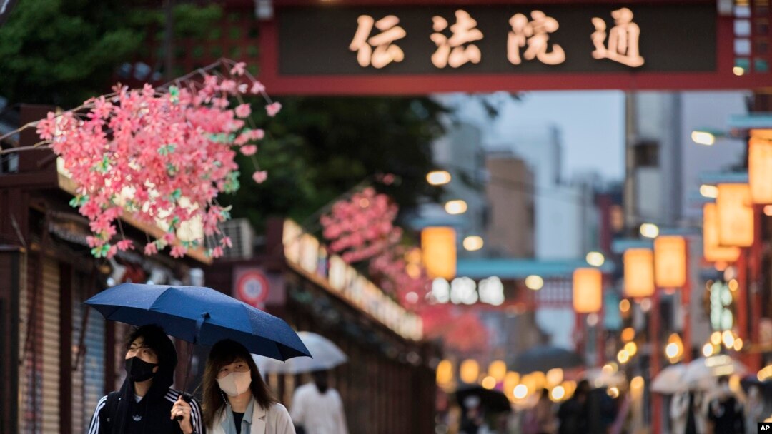 FILE - People walk through a shopping street along the famed Sensoji temple in the Asakusa neighborhood in Tokyo, April 29, 2021.
