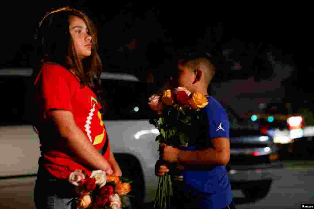 Children holding flowers stand outside the Ssgt. Willie de Leon Civic Center, where students had been transported from Robb Elementary School after a shooting, in Uvalde, Texas, May 24, 2022.