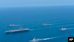 资料照:这张由日本海上自卫队提供的照片显示,2022年4月12日,在日本海举行的美日双边演习中,林肯号航母(左)和金刚号护卫舰(前)编队航行。(美联社)