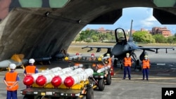 台湾军队士兵站在F16V战机前，准备进行装载美制AGM-84鱼叉反舰导弹及AIM-120和AIM-9空空导弹的训练。（2022年9月16日）