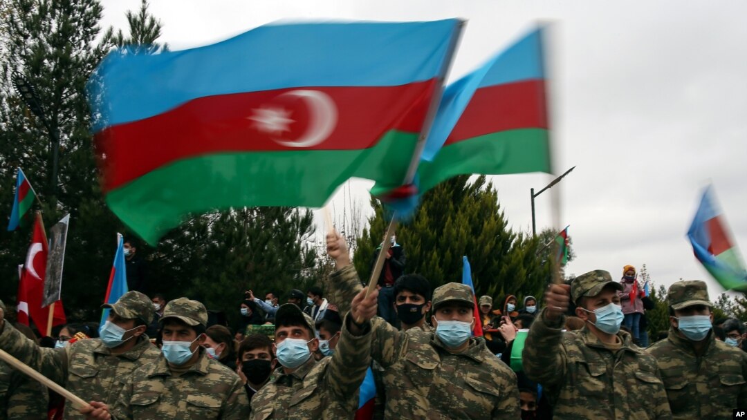 FILE - Azerbaijani soldiers wave national flags after the transfer of the Lachin region to Azerbaijani control, part of a peace deal requiring Armenia to cede Azerbaijani territories it held outside Nagorno-Karabakh, Dec. 1, 2020.