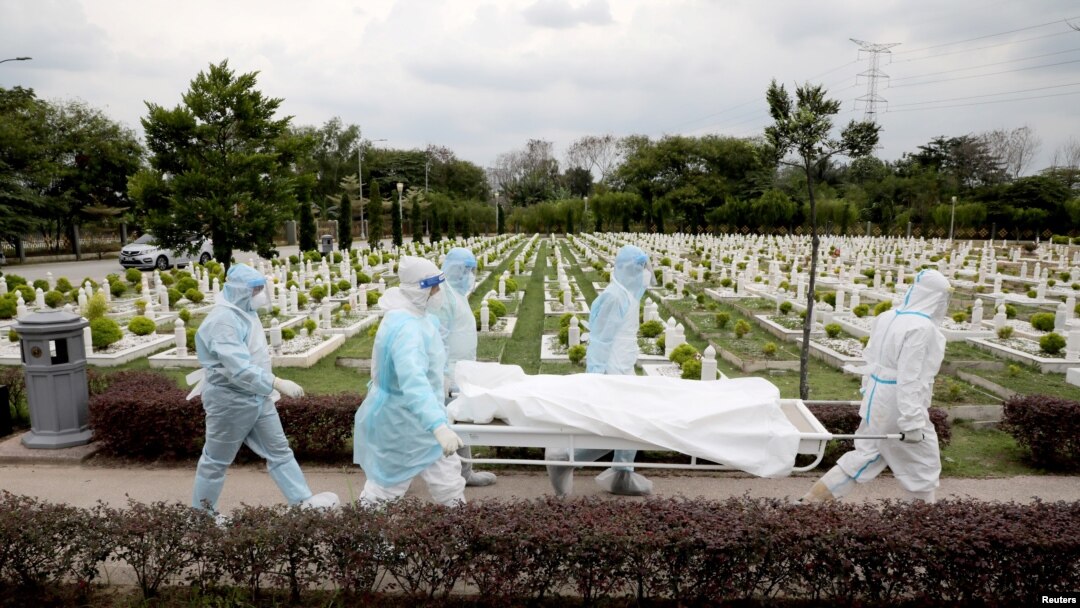 Workers wearing personal protective equipment (PPE) carry the body of a victim of the coronavirus disease (COVID-19) at a cemetery, in Batu Caves, Malaysia Jan. 27, 2021. 