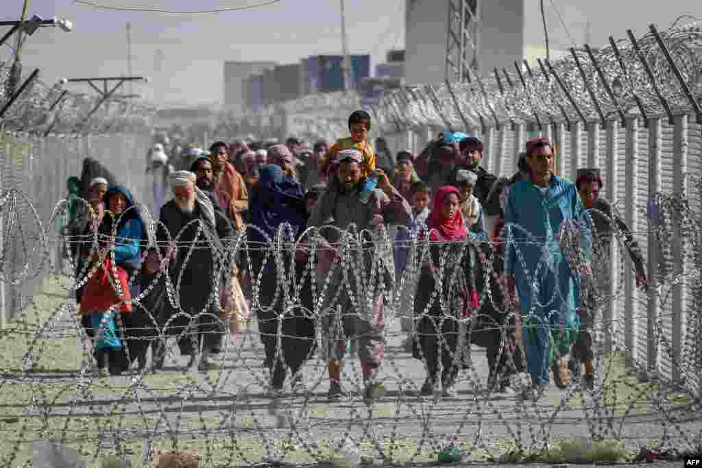 Afghans walk along fences as they arrive in Pakistan through the Pakistan-Afghanistan border crossing point in Chaman, following Taliban's military takeover of Afghanistan.