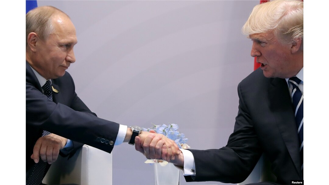 FILE - U.S. President Donald Trump shakes hands with Russian President Vladimir Putin during the their bilateral meeting at the G-20 summit in Hamburg, Germany, July 7, 2017. Trump has been criticized by former top U.S. intelligence officials for telling Putin it was a “great honor” to meet him.