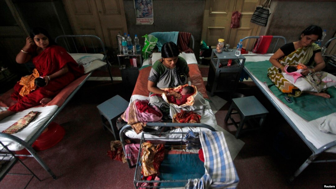 FILE - Mothers hold their newborn babies as they rest inside a maternity hospital, in Kolkata, July 11, 2012.