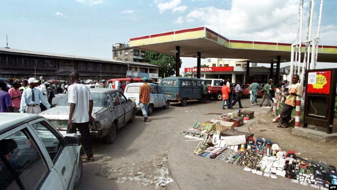 Mituka na bakumbi na yango basali molongo mpo na kozela essence na satation service na Kinshasa, 15 mai 2000.