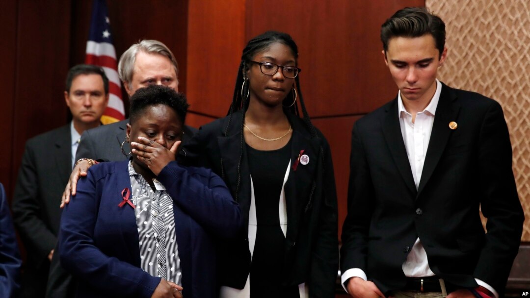 FILE - Stacey-Ann Llewellyn (L) is comforted by her daughter, Parkland, Fla., school shooting survivor Aalayah Eastmond, as David Hogg, a student at Marjory Stoneman Douglas High School, reacts while a librarian from the school recounts her experience during the shooting, March 22, 2018, on Capitol Hill in Washington. 