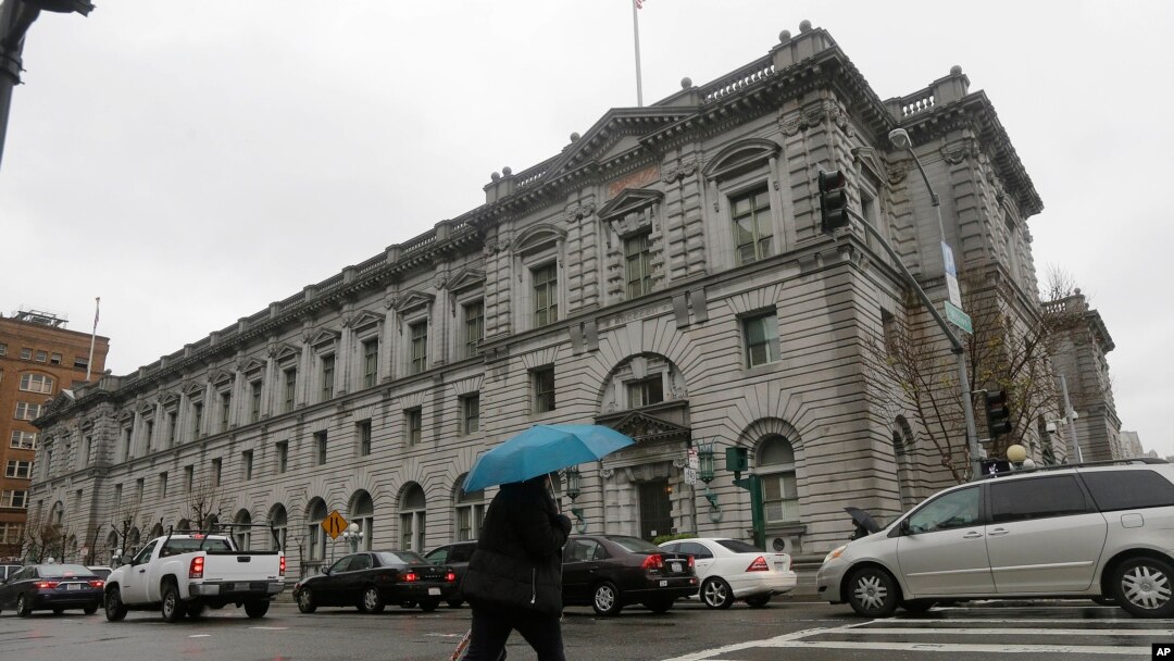 A woman crosses the street outside of the 9th U.S. Circuit Court of Appeals in San Francisco, Feb. 8, 2017. A federal appeals court will decide by end of day Thursday whether to reinstate President Donald Trump's controversial travel ban.