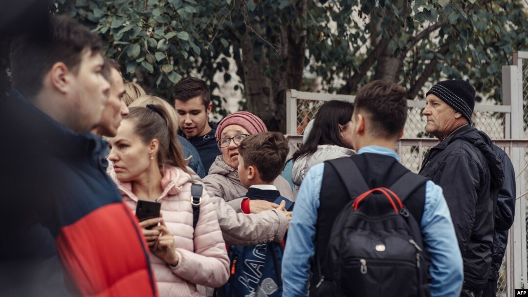 A woman hugs a boy surrounded by other people near the scene of a shooting at a school in Izhevsk, Russia, Sept. 26, 2022.