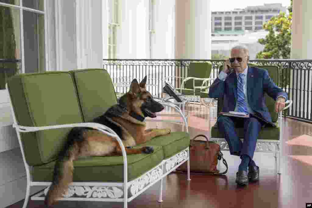In this image provided by the White House, President Joe Biden speaks on the phone with chief of staff Ron Klain from the Truman Balcony, July 25, 2022, at the White House in Washington.