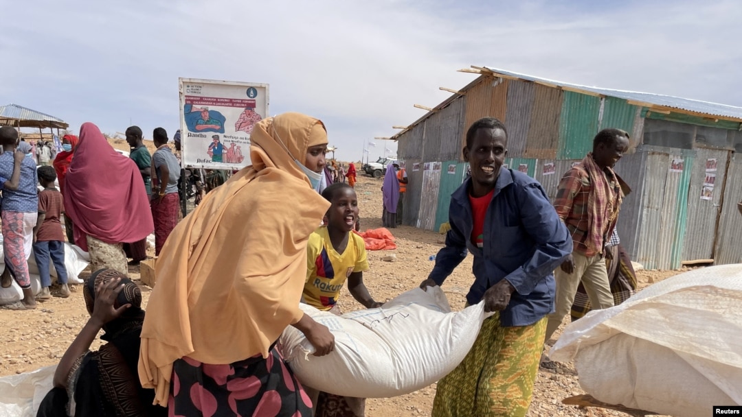 FILE - People carry bags of relief grains at a camp for the Internally Displaced People in Adadle district in the Somali region, Ethiopia, Jan. 22, 2022. Courtesy: Claire Nevill/World Food Program
