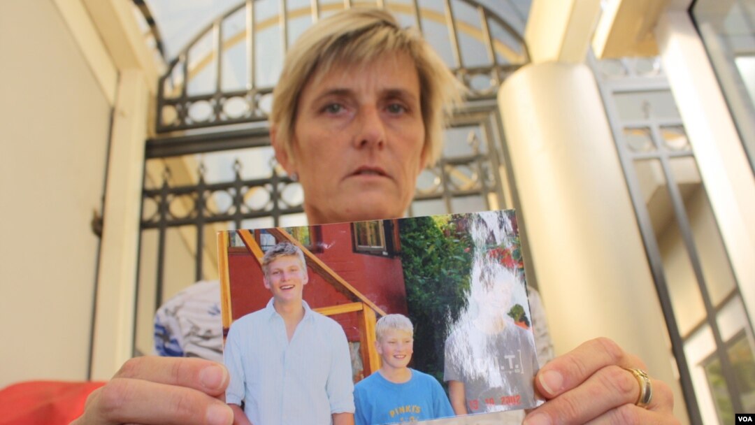Brenda Caplen holds a photo of her son, Stuart (far left in photograph), who was killed in a collision in which alcohol was a deemed major causal factor. (D. Taylor/VOA)