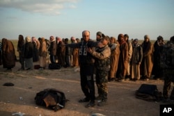FILE - A man is frisked by a U.S.-backed Syrian Democratic Forces fighter after being evacuated from the last territory held by Islamic State militants, near Baghuz, Syria, Feb. 22, 2019.