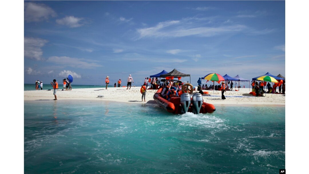 FILE - Chinese tourists enjoy scenic Quanfu Island, one of Paracel Islands of Sansha prefecture of southern China's Hainan province, Sept. 14, 2014.
