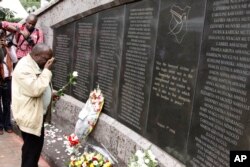FILE - An unidentified man lays flowers at the US Embassy bombing memorial site in Nairobi, Kenya, Aug. 7, 2013.